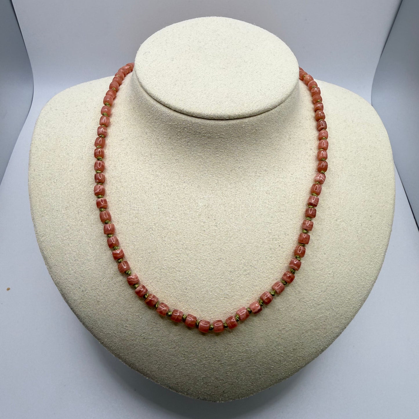 Pink beaded necklace on white display bust