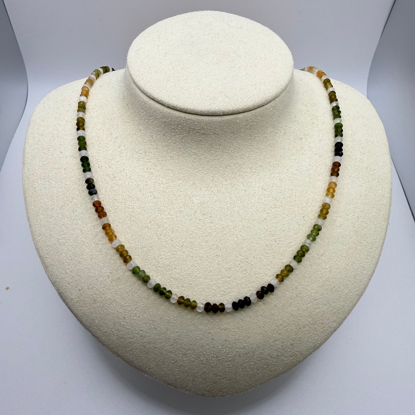 Beaded necklace in yellows and greens on a white display bust