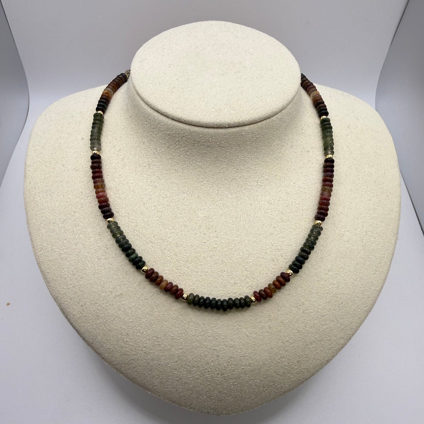 Necklace with multicolored earth toned beads on a white display bust