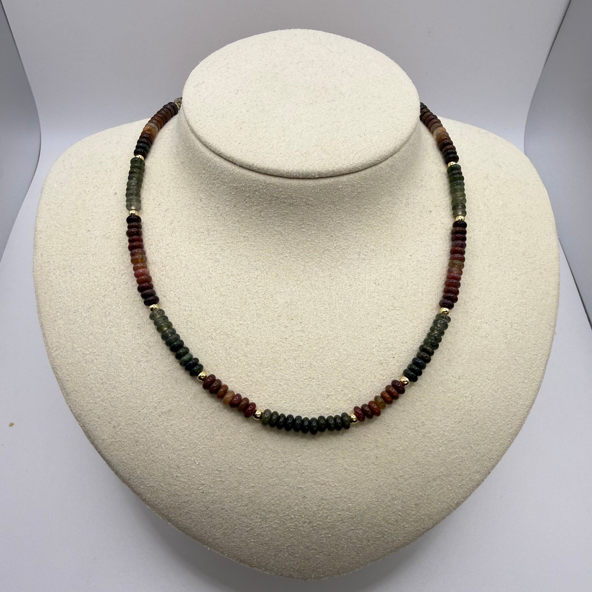 Necklace with multicolored earth toned beads on a white display bust
