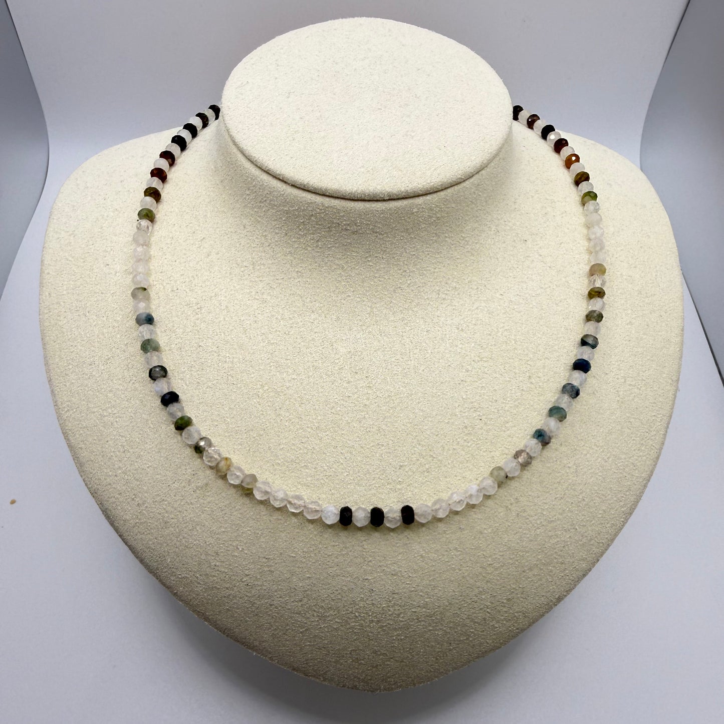 White and green beaded necklace on a white display bust.