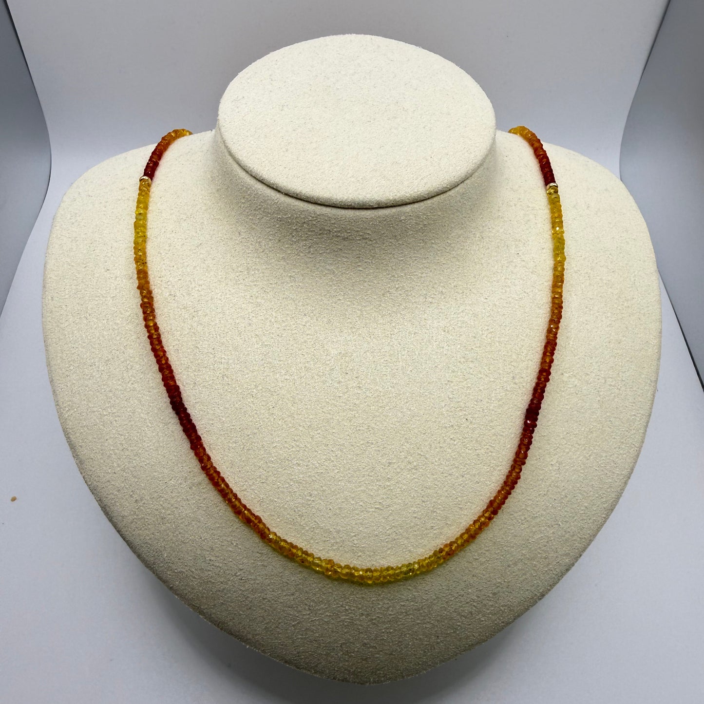 Orange and yellow beaded necklace on a white display bust
