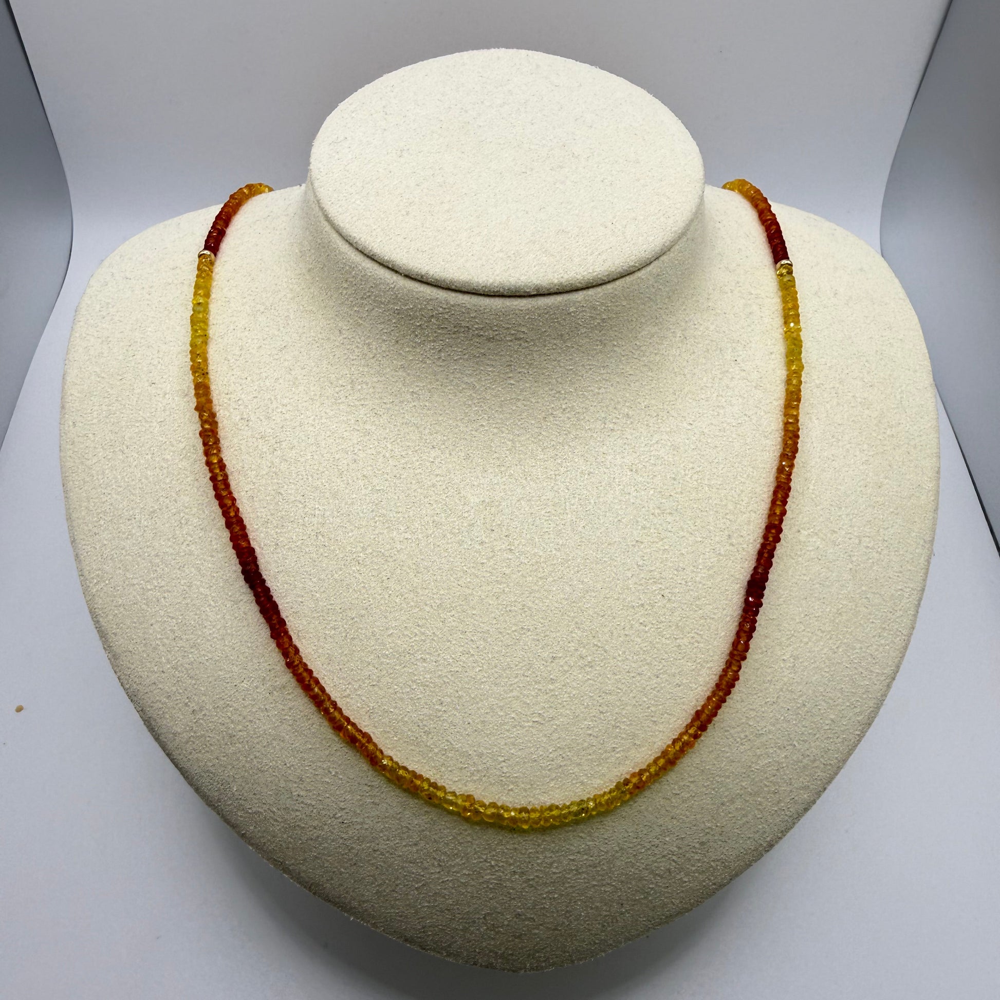 Orange and yellow beaded necklace on a white display bust