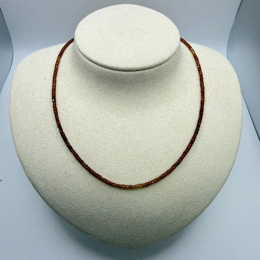 Brown beaded necklace on a white display bust.
