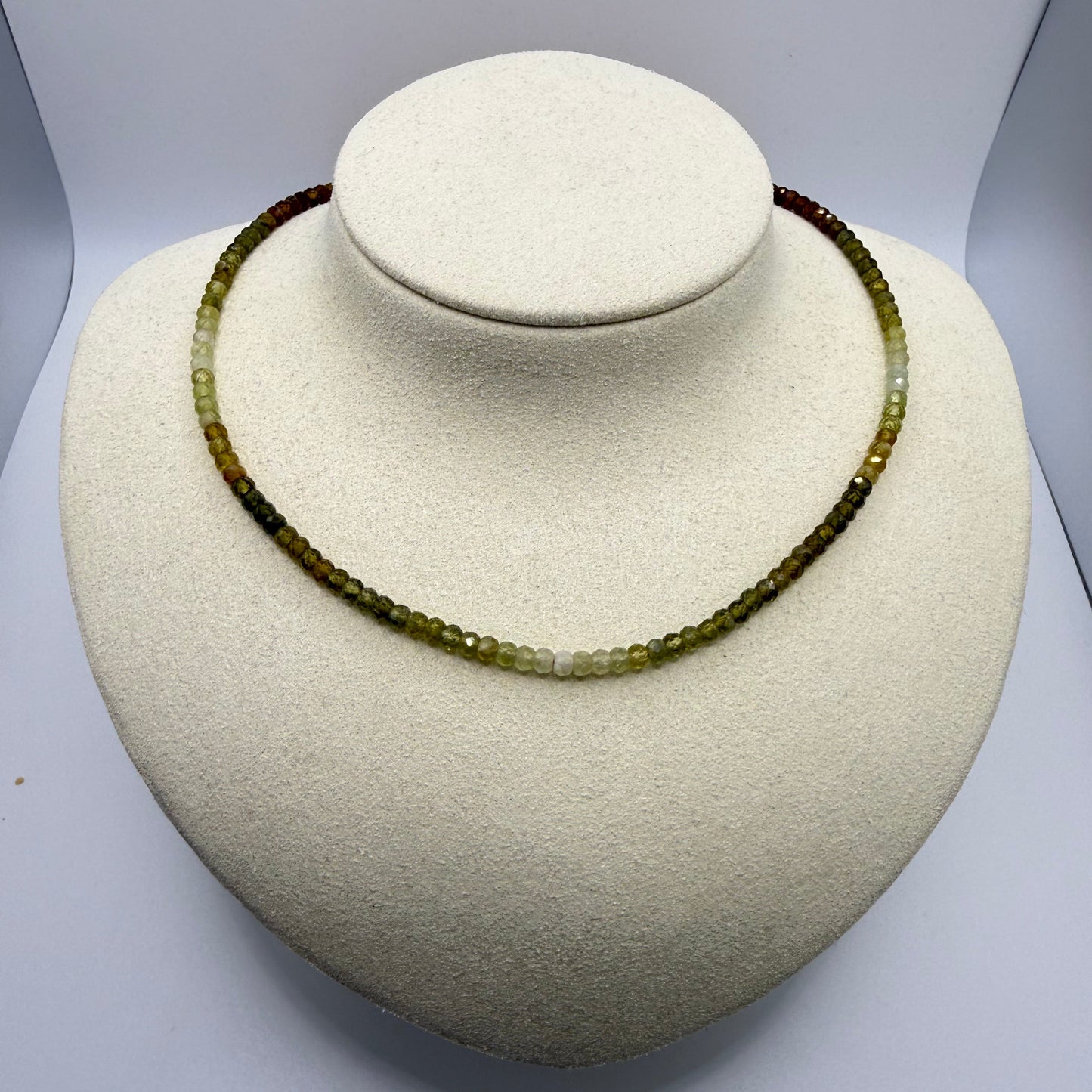 Green beaded necklace on a white display bust.
