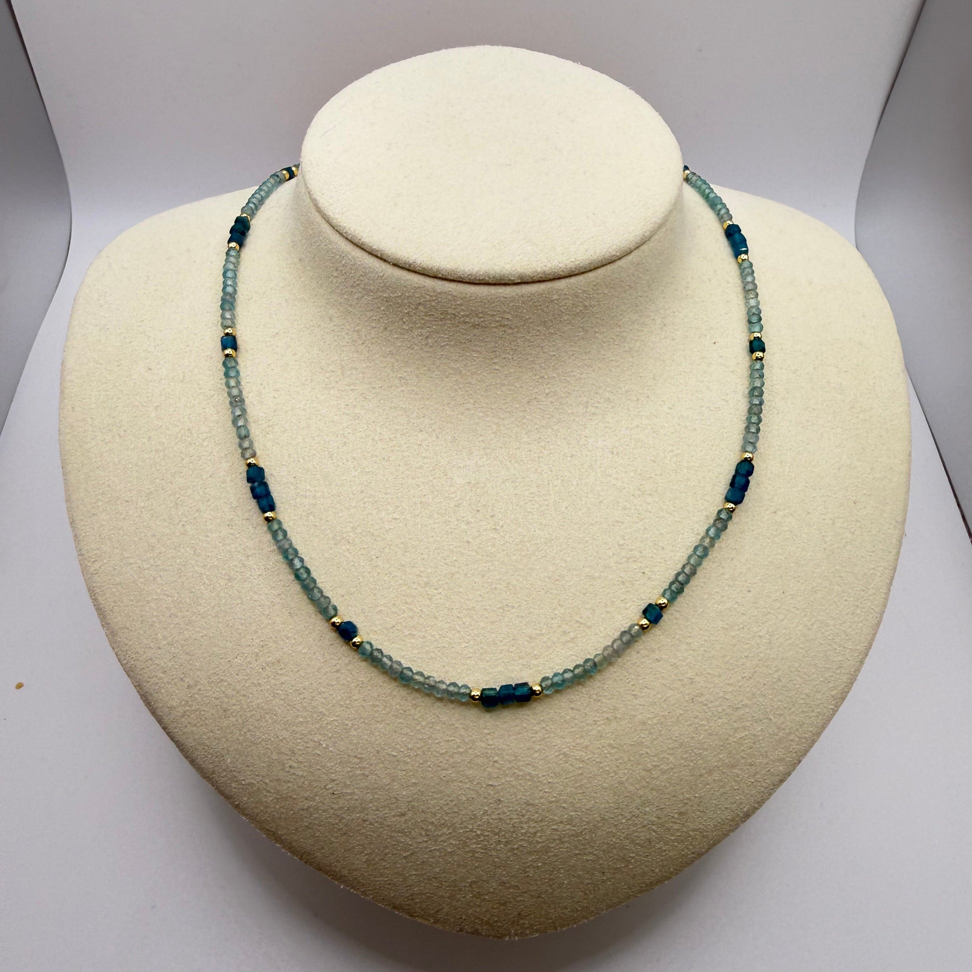 Blue beaded necklace on a white display bust.