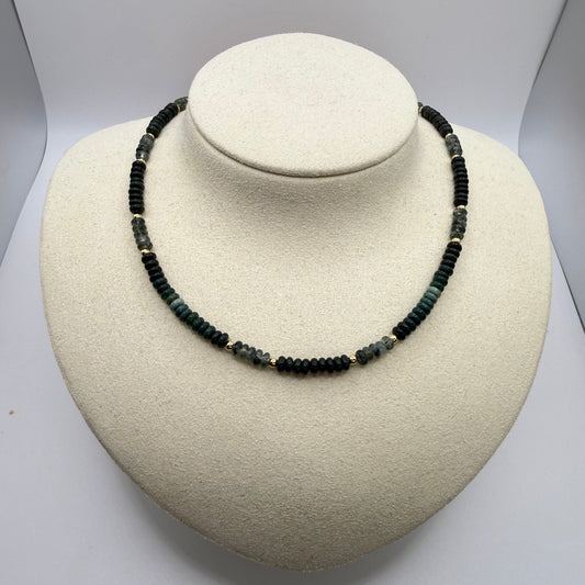 Necklace with green beads on a white display bust.