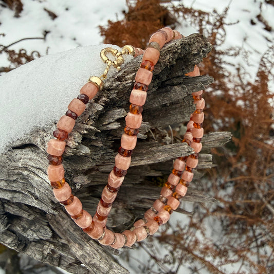 A beaded necklace wrapped over a textured surface with a snowy background