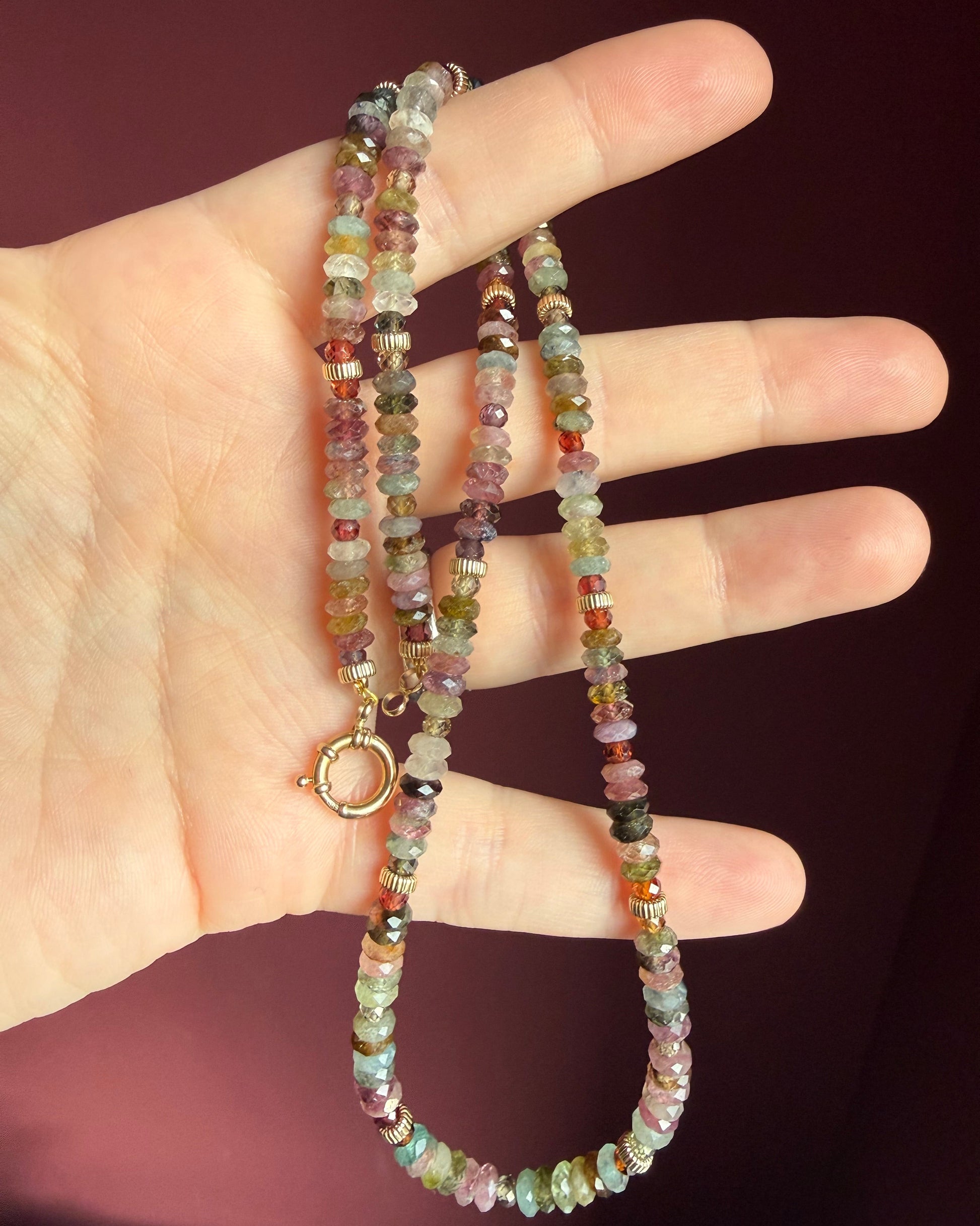 Multicolored beaded necklace on a hand with a dark background
