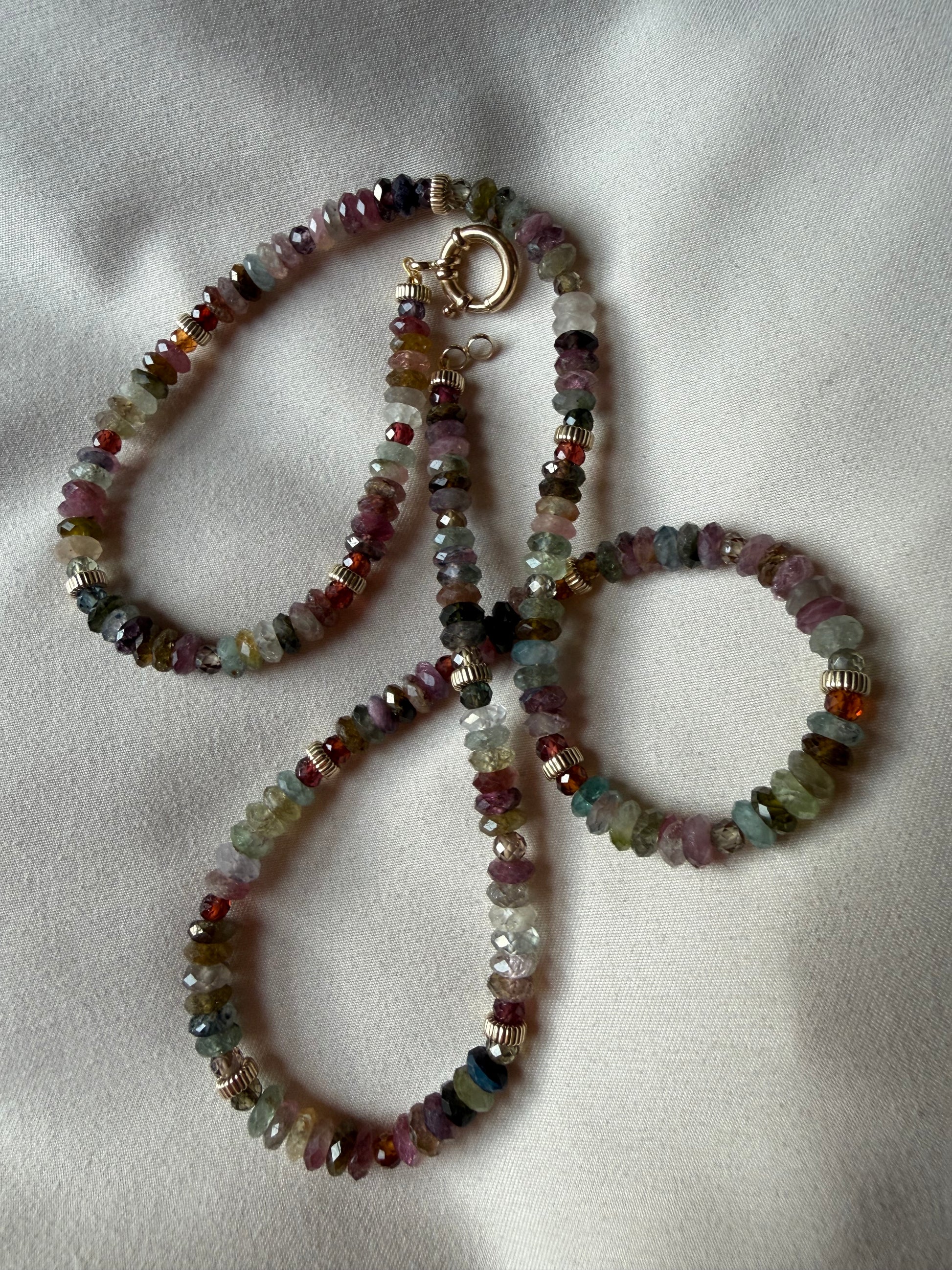 Multicolored beaded necklace and bracelet on a light fabric background
