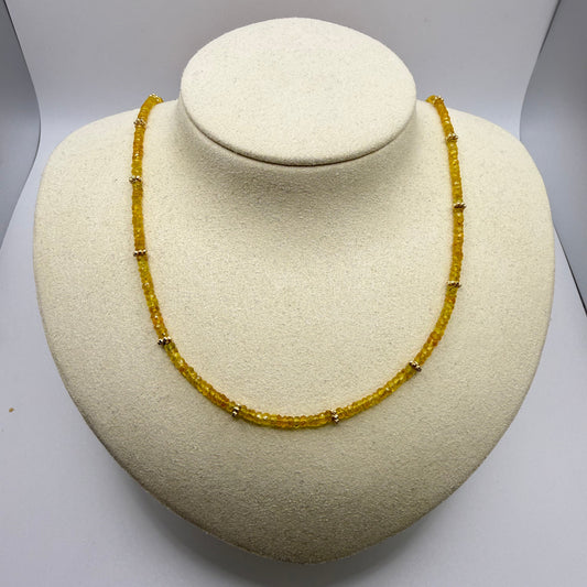 Yellow gemstone necklace on a beige textured display bust