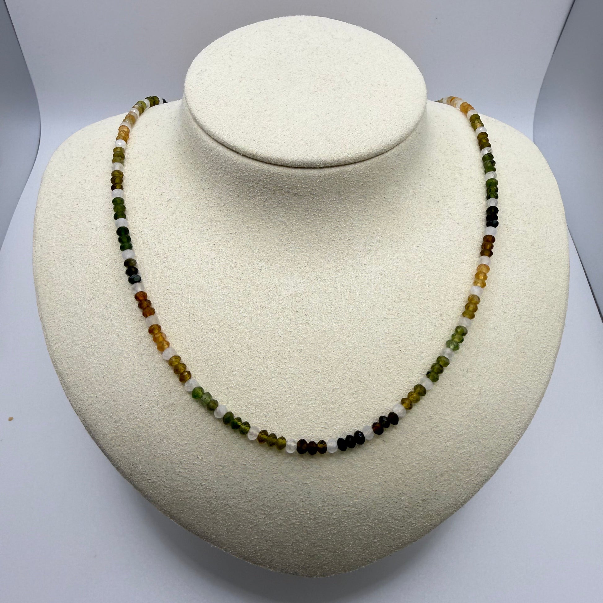 Beaded necklace in yellows and greens on a white display bust
