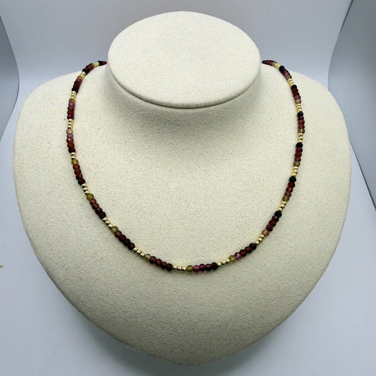 Necklace with brown and gold beads on a white display bust
